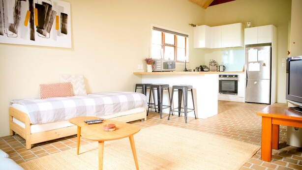 A compact living space with a kitchenette, a sofa, a small dining table, and a TV.