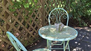 Two outdoor metal chairs with a woven seat and backrest, positioned on a tiled patio with a wooden lattice fence in the background.