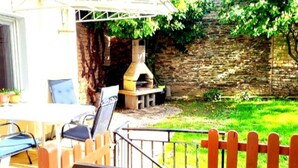 Un patio al aire libre con un muro de piedra, un horno de ladrillo y una zona de estar con sillas y una mesa.