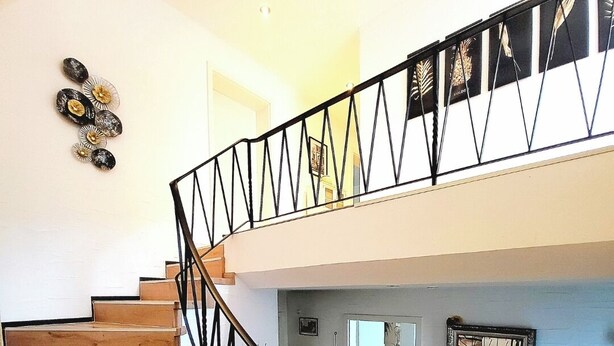 Una escalera de madera con barandilla negra que conduce a un piso superior.