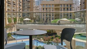 A balcony with a pool view, outdoor seating, and a bridge. - STYLO Residences & Suites (Tashkent)