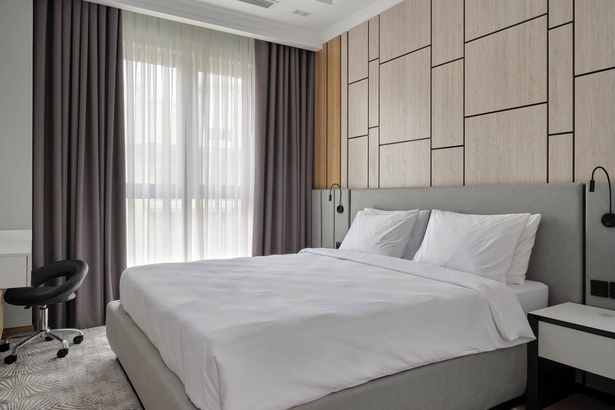Une chambre d’hôtel moderne avec un grand lit, un bureau et une chaise.