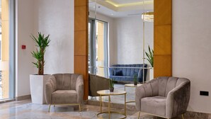 A modern lobby with two plush armchairs, a small round table, and a blue sofa. - STYLO Residences & Suites (Tashkent)