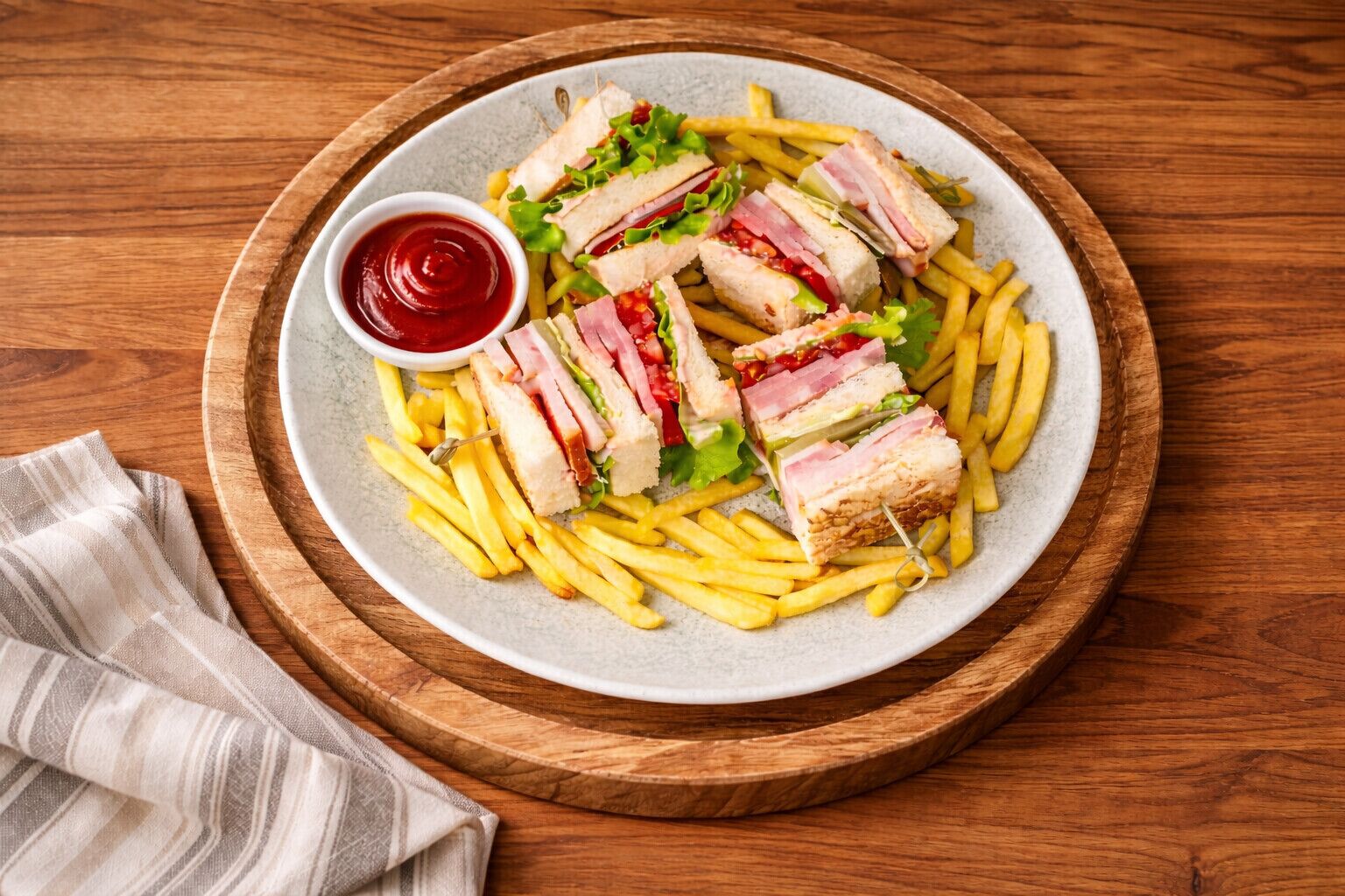 A plate of French fries and a sandwich with a side of ketchup.