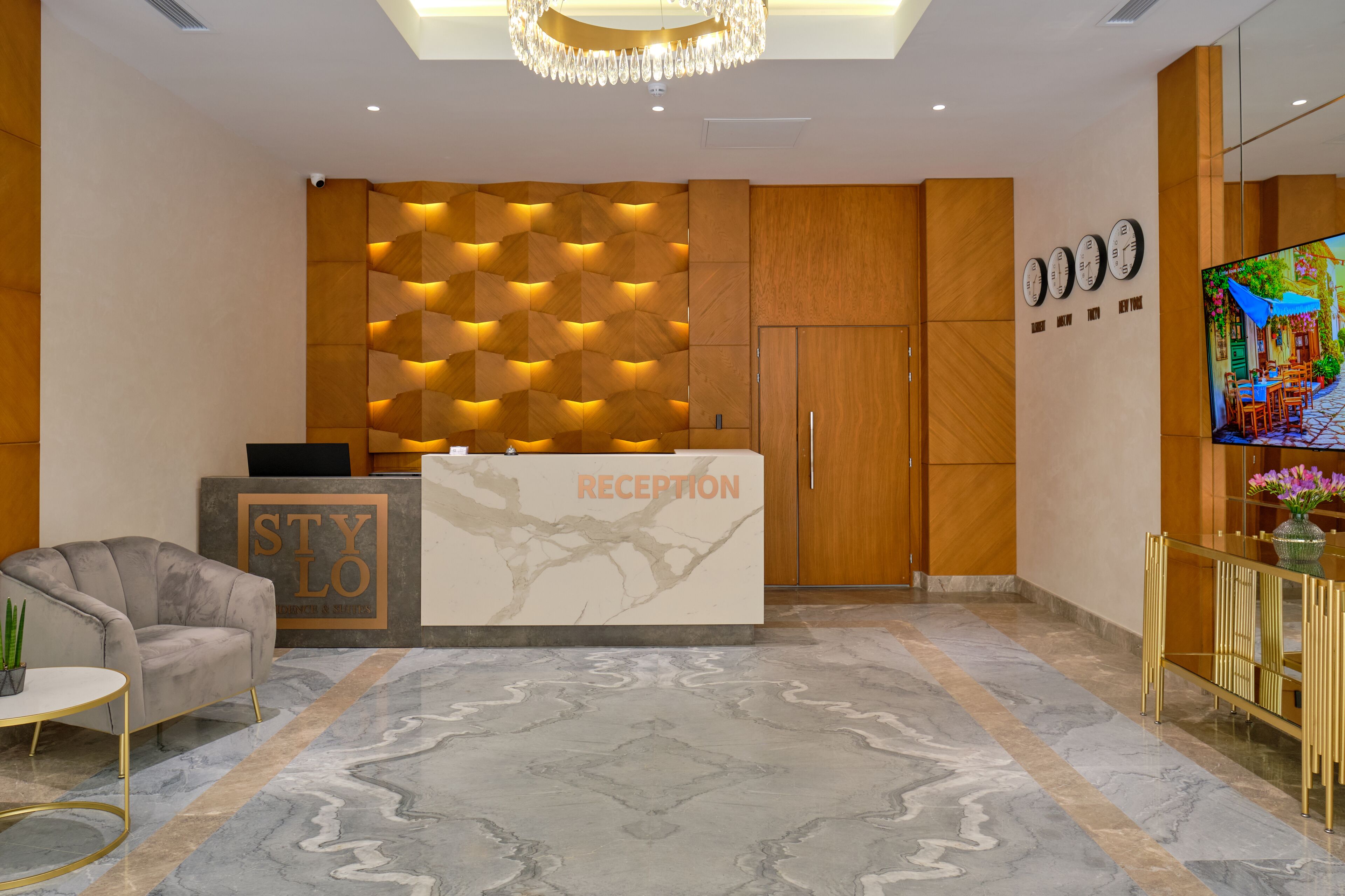 A reception area with a marble floor, a reception desk, a sofa, a TV, and wooden paneling.