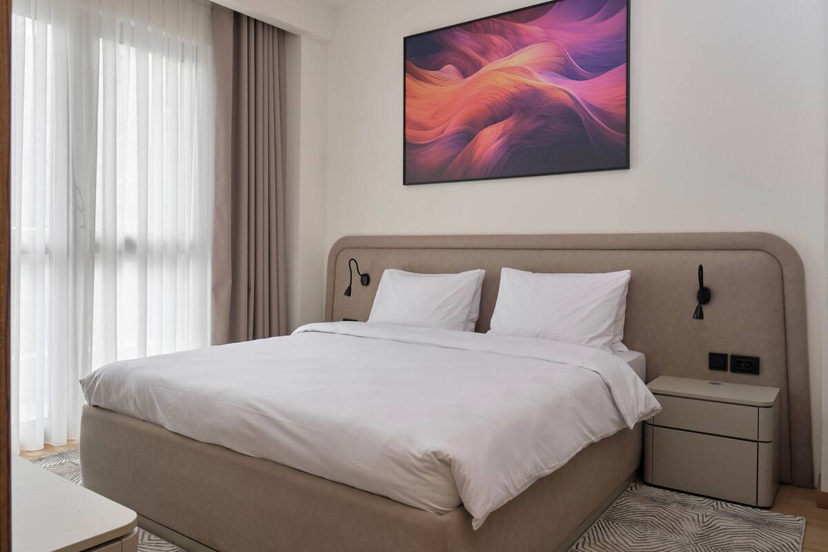 Une chambre d’hôtel moderne avec un grand lit, une table de chevet et une petite table d’appoint.