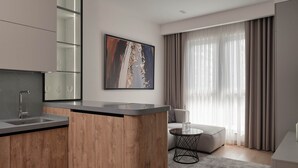 A modern kitchen with a wooden island, a built-in wine rack, and a dining area with a round table and sofa. - STYLO Residences & Suites (Tashkent)