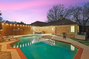 A backyard with a swimming pool, wooden deck, and a hammock. - 5BR DeSoto Home | Pool, Game Room & Theater (DeSoto)