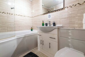 A bathroom with a bathtub, a sink, and a toilet. There is a mirror above the sink and a QR code on the wall. - 2BR Apartment in the Heart of Leeds City Centre (West Yorkshire)