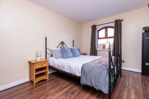 A bedroom with a bed, wooden nightstand, and a window with curtains. - 2BR Apartment in the Heart of Leeds City Centre (West Yorkshire)