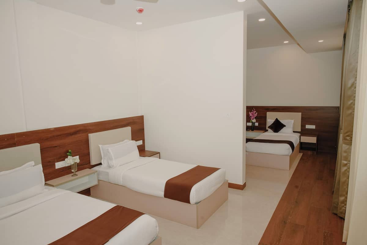 Habitación de hotel con dos camas, cabecero de madera, mesita de noche con un florero y suelo de madera.