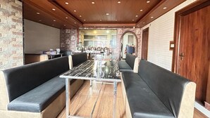 A dining area with a marble table, black cushioned benches, and a brick wall. - RATNA VILLA INN (Darjeeling)