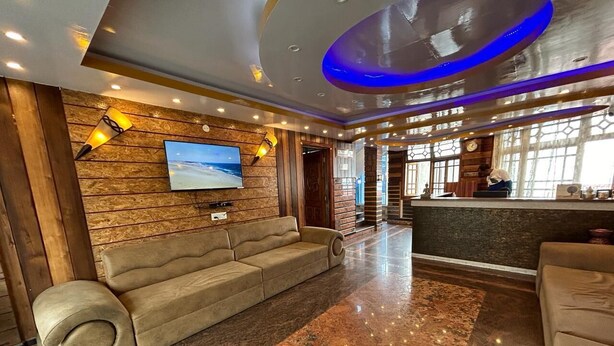 A lobby with a sofa, a TV, and a reception desk. - RATNA VILLA INN (Darjeeling)