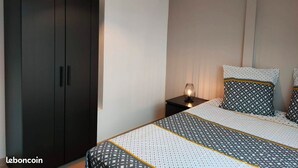 Een slaapkamer met een bed, een kledingkast en een nachtkastje met een lamp.