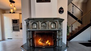 Een moderne woonkamer met een ingebouwde open haard, een trap en een keuken op de achtergrond.