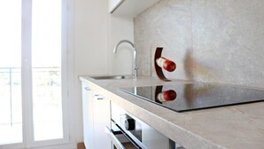 A modern kitchen with a glass countertop, stainless steel sink, and a view of the outdoors.