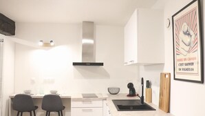 Een moderne keuken met witte kastjes, een zwarte kookplaat en twee barkrukken.
