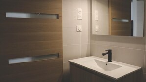 Een moderne badkamer met een houten wastafelmeubel, een witte wasbak en een spiegel.