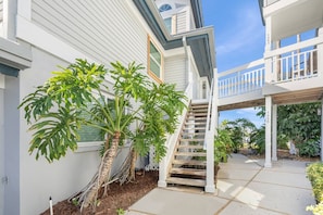 A residential property with a covered outdoor staircase, a white fence, and a well-maintained garden with large-leafed plants. - On the Bay - great views! Walk to Priv Beach, Pool (Siesta Key)