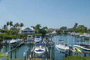 A marina with boats docked at wooden piers, surrounded by greenery and a clear sky. - On the Bay - great views! Walk to Priv Beach, Pool (Siesta Key)