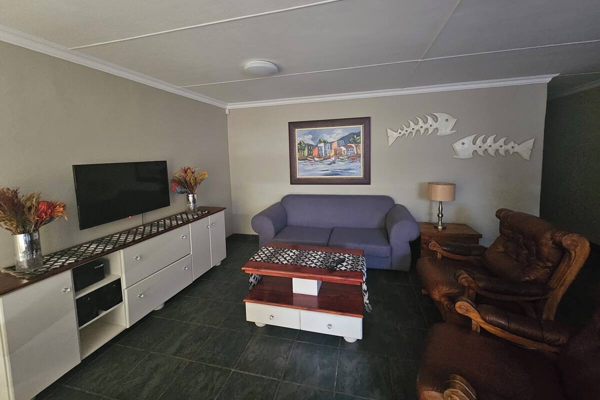 A living room with a flat-screen TV, a sofa, a coffee table, a cabinet, and a chair.