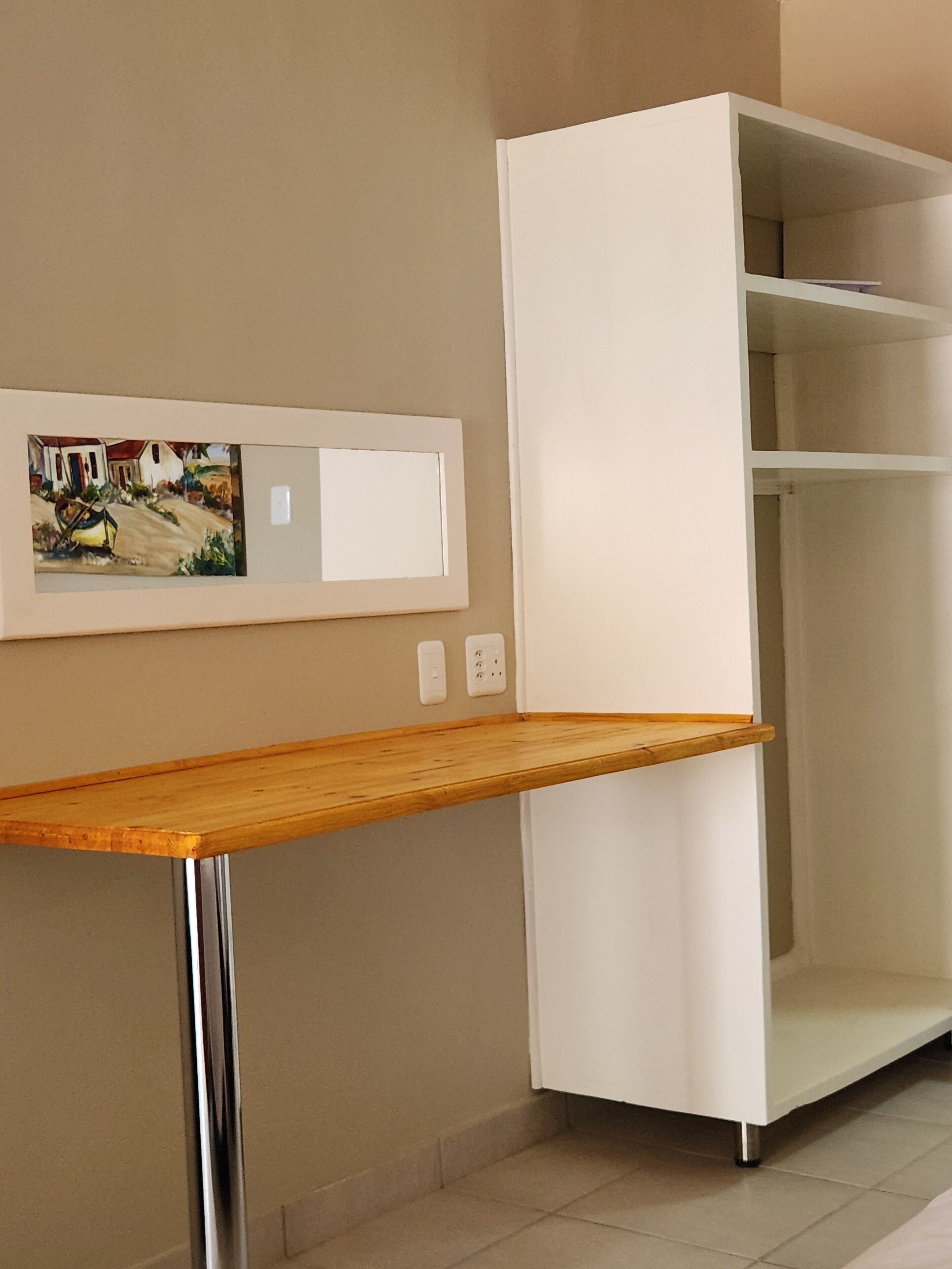 A room with a wooden table, a white wardrobe, and a framed picture on the wall.
