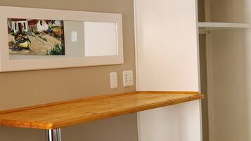 A room with a wooden table, a white wardrobe, and a framed picture on the wall.