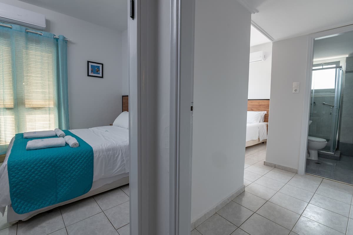 Una habitación de hotel con cama, baño con ducha y vista a otra habitación.