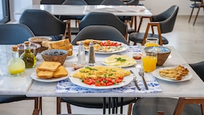 Une table de petit-déjeuner avec divers plats, notamment des toasts, des œufs, des tomates et un verre de jus d’orange.