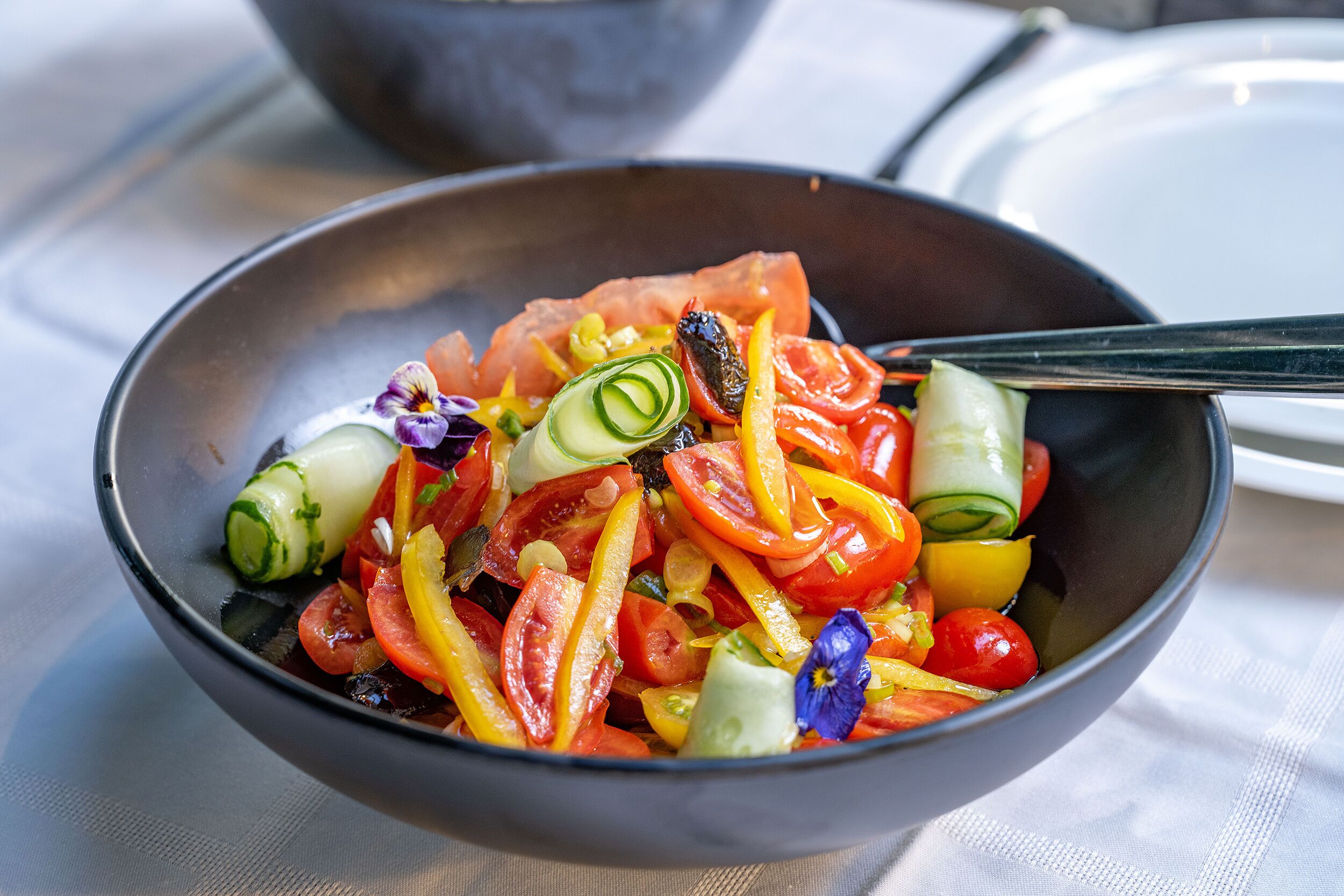 Un saladier rempli d’une salade de légumes colorée, composée de divers légumes et agrémentée d’une fleur bleue.