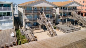 A multi-story hotel with outdoor wooden decks and multiple staircases leading to balconies. - 1911 Oceanblock Summa (Ocean City)