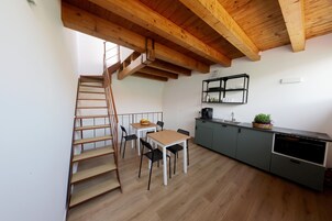 A kitchen with a wooden staircase, a dining table with chairs, and a built-in oven.