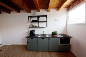 A compact kitchen with a built-in shelf, a sink, and a coffee maker.