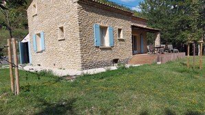Una casa de piedra con una terraza de madera, una puerta y una ventana.