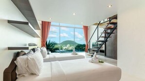 A modern hotel room with a large bed, a view of a mountain, and a staircase. - Hilltop Wellness Living (Ratsada)