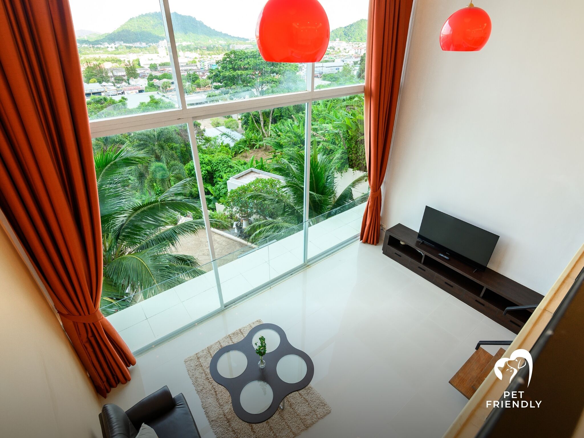 A modern living room with a large window, a flat-screen TV, and a cozy seating area.