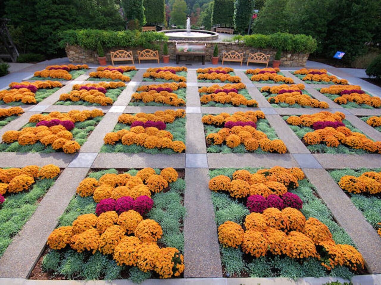 Ein Garten mit Brunnen, angelegten Blumenbeeten und Sitzbereichen.
