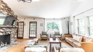 Un salon chaleureux avec une cheminée en pierre, un plancher en bois, un canapé, des fauteuils et une table basse.