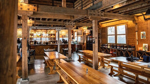 Un intérieur rustique en bois, avec des poutres apparentes, des tables et des bancs en bois.