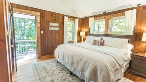 Une chambre avec un grand lit, des murs en bois et une vue sur l’extérieur.