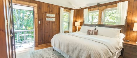 Een slaapkamer met een groot bed, houten wanden en uitzicht op het omliggende landschap.