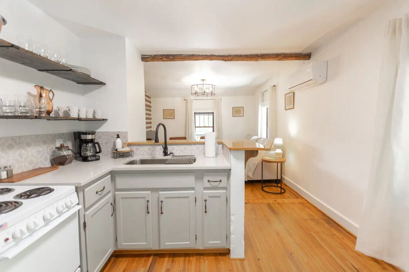 A compact kitchen with a stove, sink, and wooden flooring.