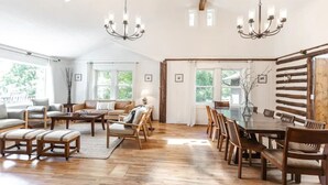 Un salón espacioso con piso de madera, una gran mesa de comedor con sillas y una araña.