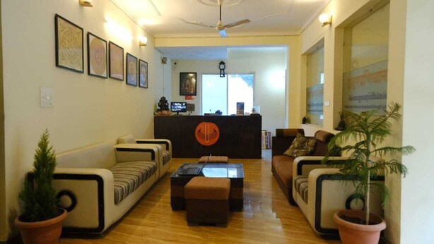 A modern living room with a sofa set, a coffee table, and a reception desk. - Vardan Hotel- Ayur Stay (Yamkeshwar)