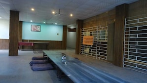 A conference room with a long table, chairs, and a projector screen. - Vardan Hotel- Ayur Stay (Yamkeshwar)
