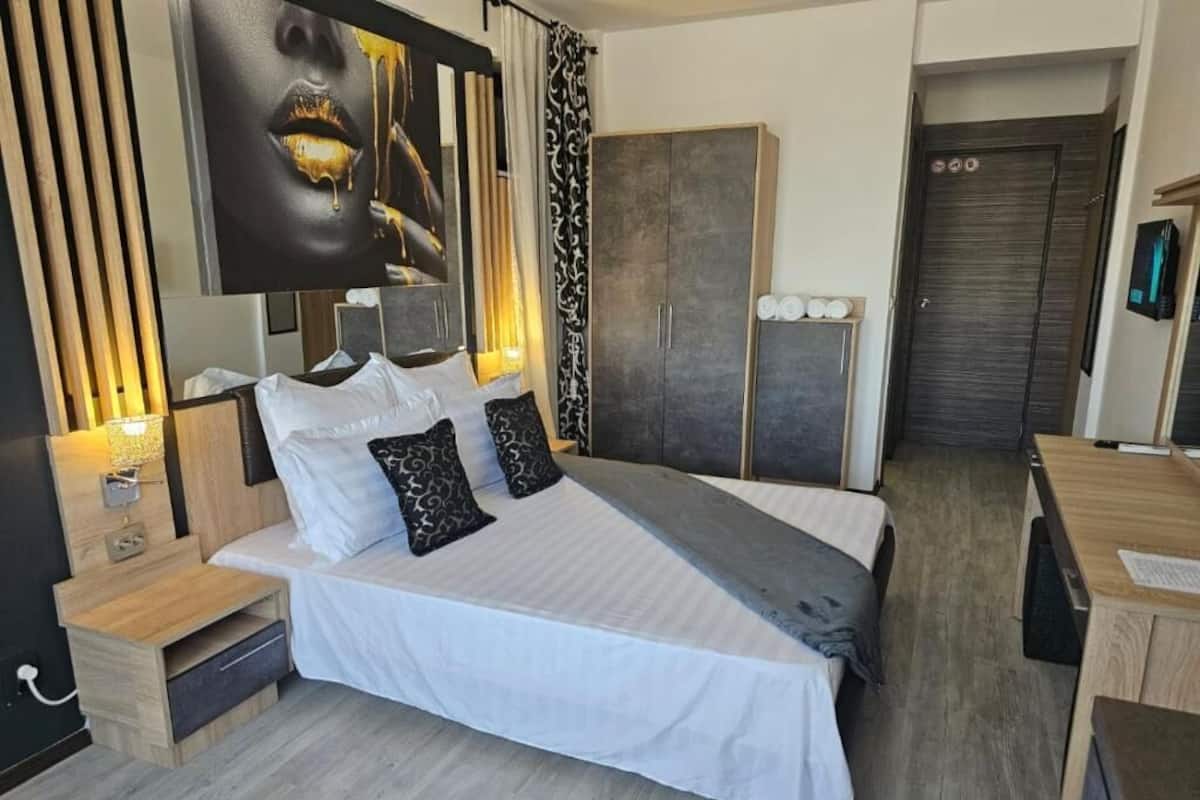 A modern bedroom with a large bed, bedside tables, a wardrobe, and a desk.