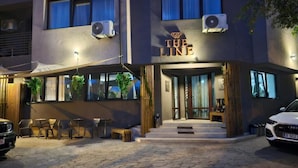 Ein Hotel namens "The Line" mit moderner Fassade, einer Sitzgelegenheit im Freien und einem parkenden Auto davor.