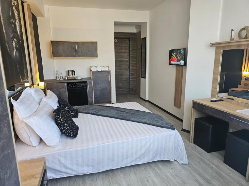 Et moderne hotelværelse med seng, skrivebord, fjernsyn og tekøkken.