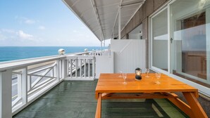 Ein Holztisch mit Gläsern und einer Laterne auf einem Balkon mit weißer Geländer, mit Blick auf das Meer.