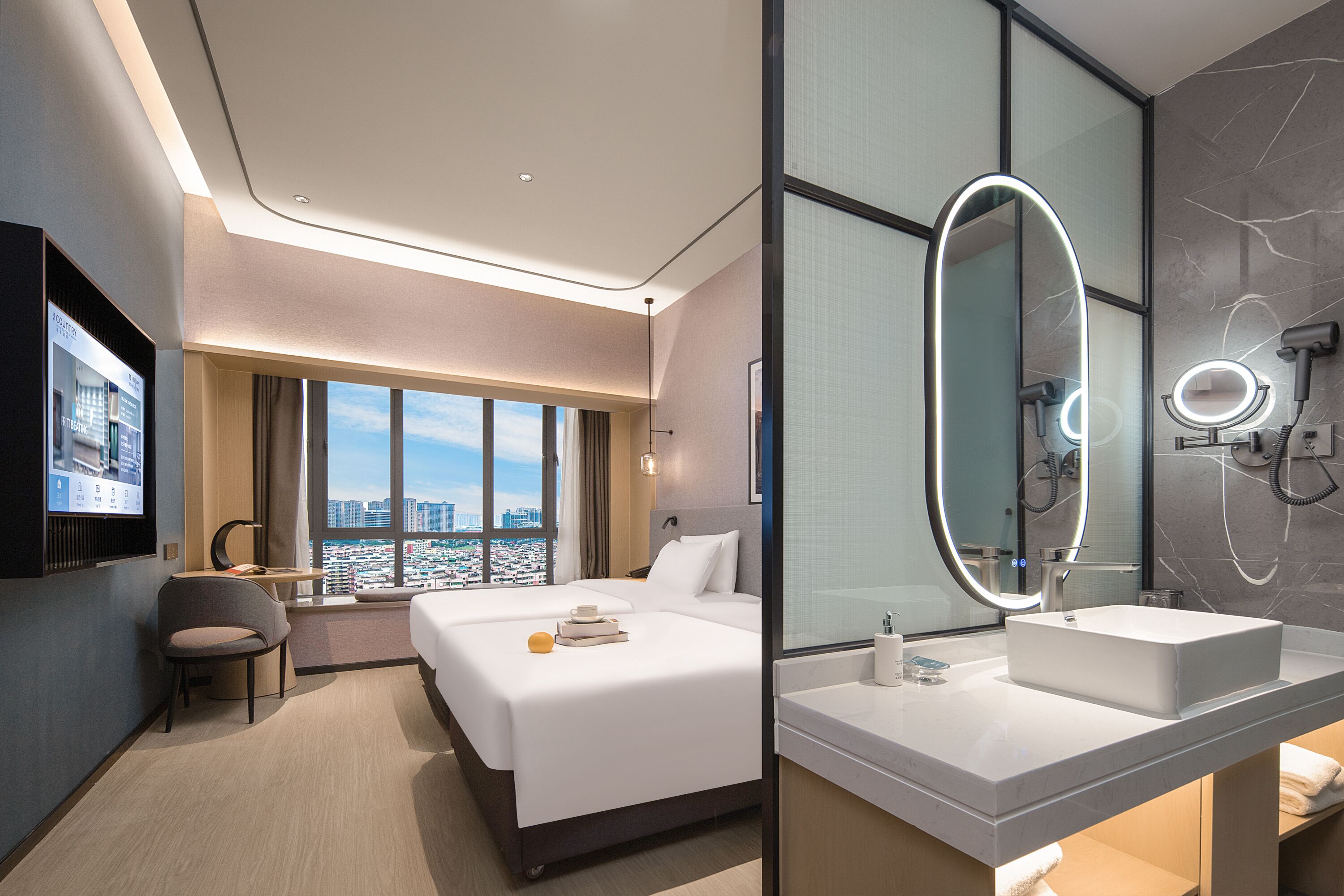Een moderne hotelkamer met een groot bed, een bureau, een stoel, een televisie, een badkamer met grote spiegel en uitzicht op de stad.